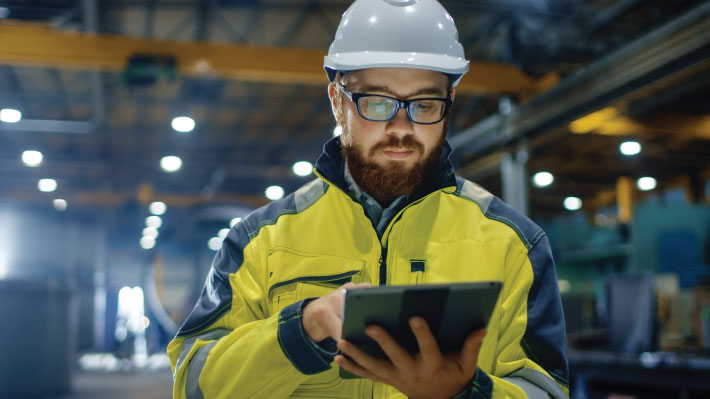 Worker completing digital form on tablet in factory